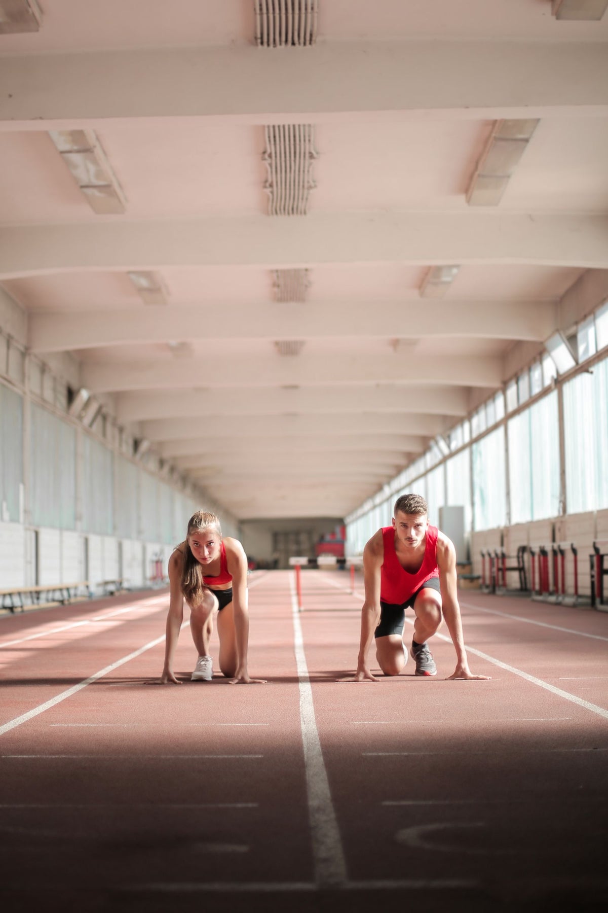 Athletes preparing to sprint on an indoor track